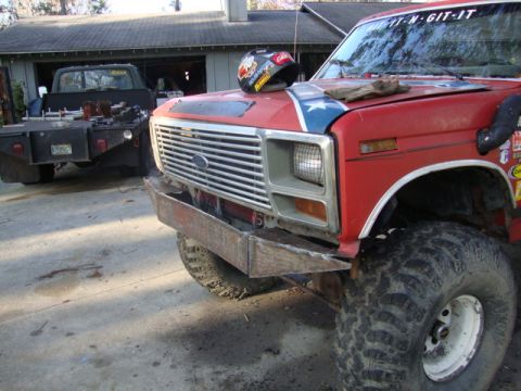 1986 Ford Bronco - A red pickup truck with a custom bumper and a Confederate flag decal on the hood is parked in a driveway.