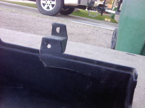 1995 Ford Probe - Close-up of a damaged black plastic car part with a metal bracket. A white truck is parked behind it.