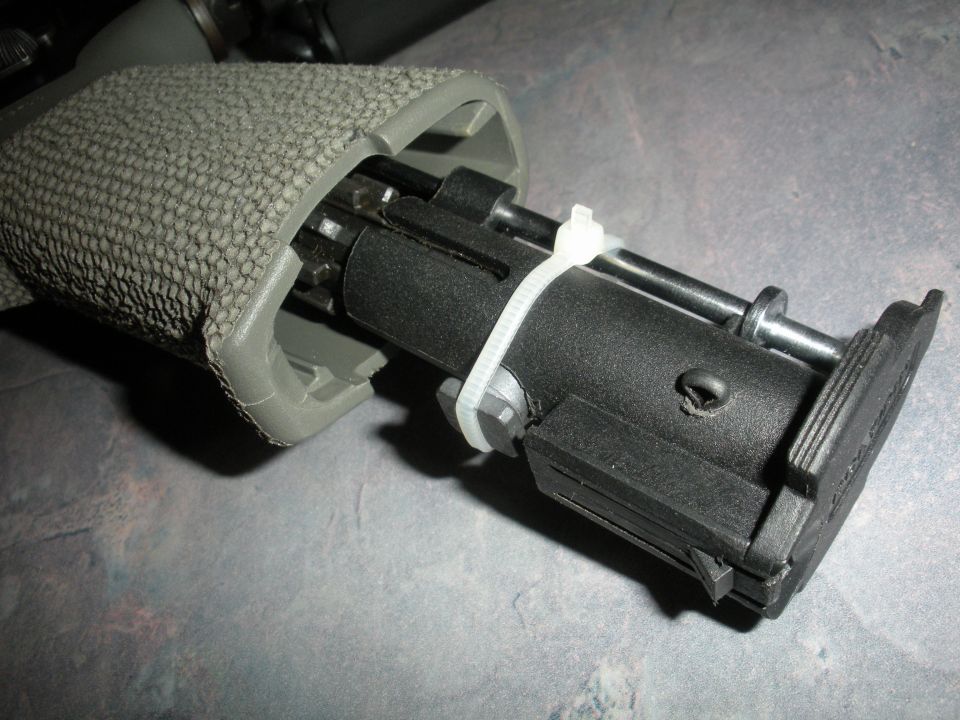 Close-up of a rifle's internal mechanism, secured with a zip tie