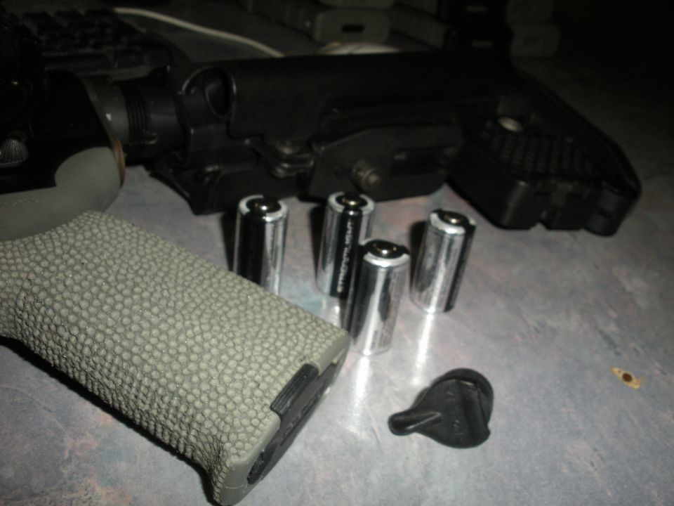 Gun grip and batteries on a surface with Supermotors logo