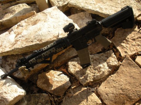 1996 Ford Bronco - Assault rifle with scope and magazine resting on rocks.