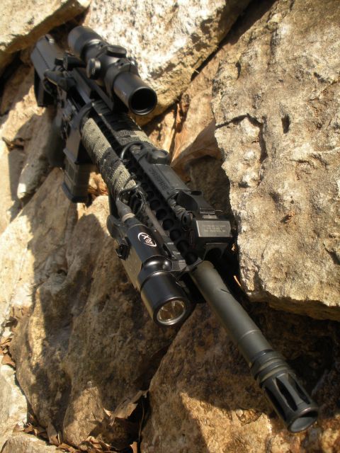 1996 Ford Bronco - A rifle equipped with a scope and flashlight rests against a rocky surface.