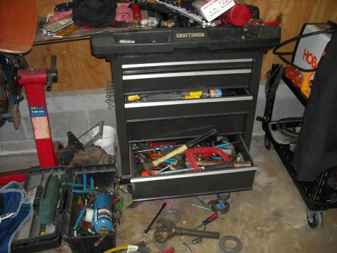 1979 Ford F-150 - A cluttered garage scene with a Craftsman tool chest and various tools on the floor and shelves.