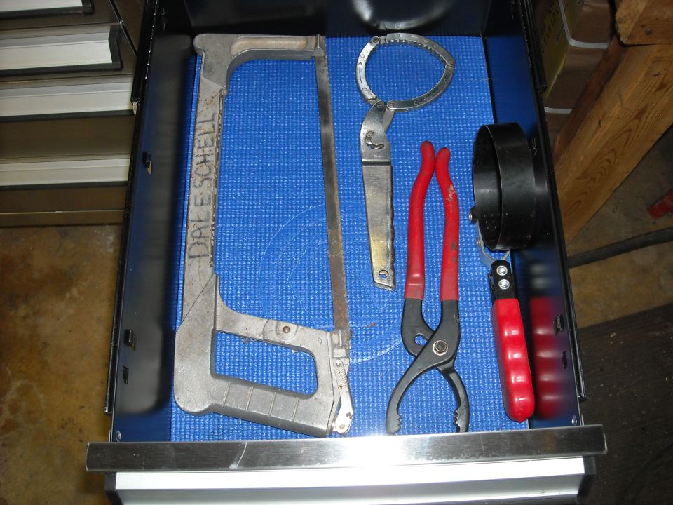 Hacksaw, oil filter wrench, pliers, and another filter wrench in a drawer