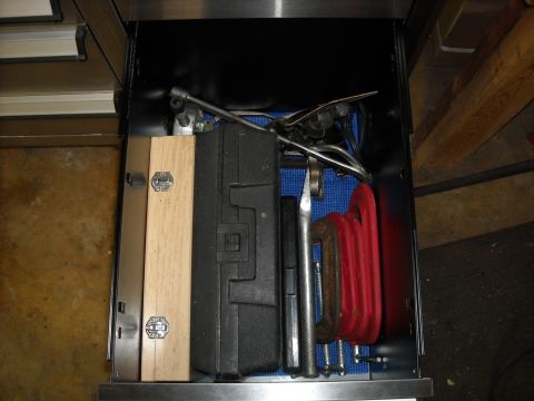 1979 Ford F-150 - A collection of tools, including clamps and a wooden case, are organized within a metal drawer.