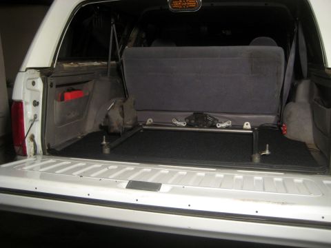 1996 Ford Bronco - The cargo area of a white 1996 Ford Bronco shows black carpeting and a folded rear seat.