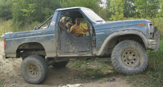 Side view of a lifted, blue 1980s Ford Bronco with aftermarket wheels