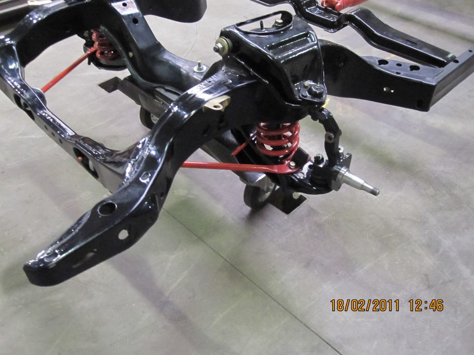 Black vehicle frame with red springs and suspension parts, viewed from the front-right