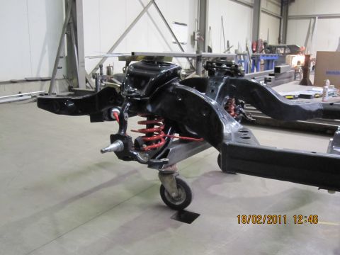 1973 Ford Ranchero - A vehicle's frame and suspension system, including red coil springs, is shown on casters in a workshop.