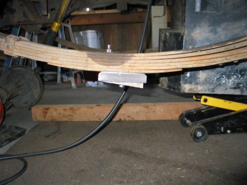1984 Ford Bronco - Leaf spring assembly supported by a jack and blocks, likely during maintenance or modification.