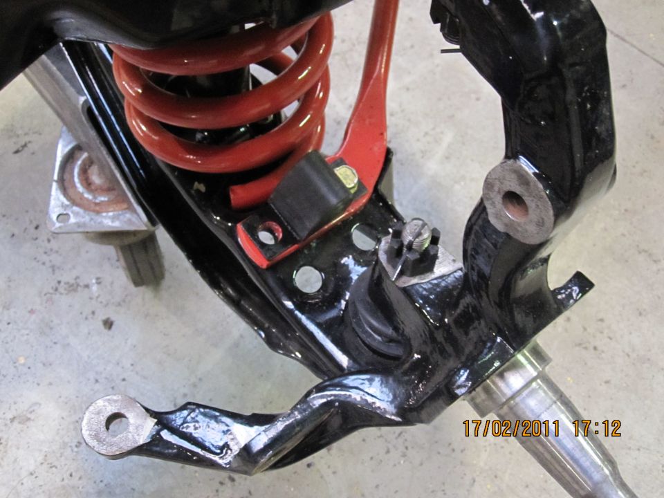 Black painted suspension part with red coil spring, showing a date stamp and website