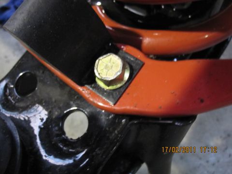 1973 Ford Ranchero - Close-up view of a vehicle suspension component, showing orange and black painted metal with a bolt fastener.