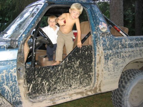 1986 Ford Bronco - Two young boys stand inside a heavily mud-covered 1986 Ford Bronco, ready for adventure.