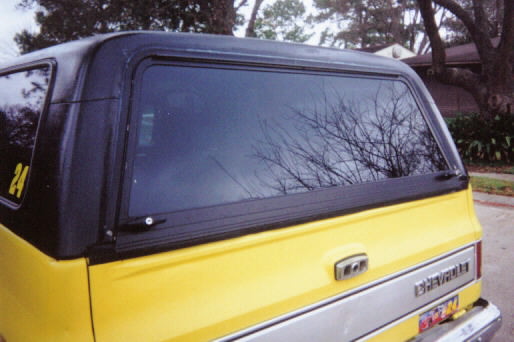 Rear of yellow and black Chevrolet SUV with tinted windows on a driveway