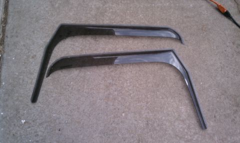 2005 Jeep Wrangler - A pair of dark plastic window visors are shown lying on a concrete surface.