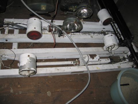 2001 Ford Crown Victoria - A collection of lights and wiring is mounted on a white metal frame, resting on a wooden floor.