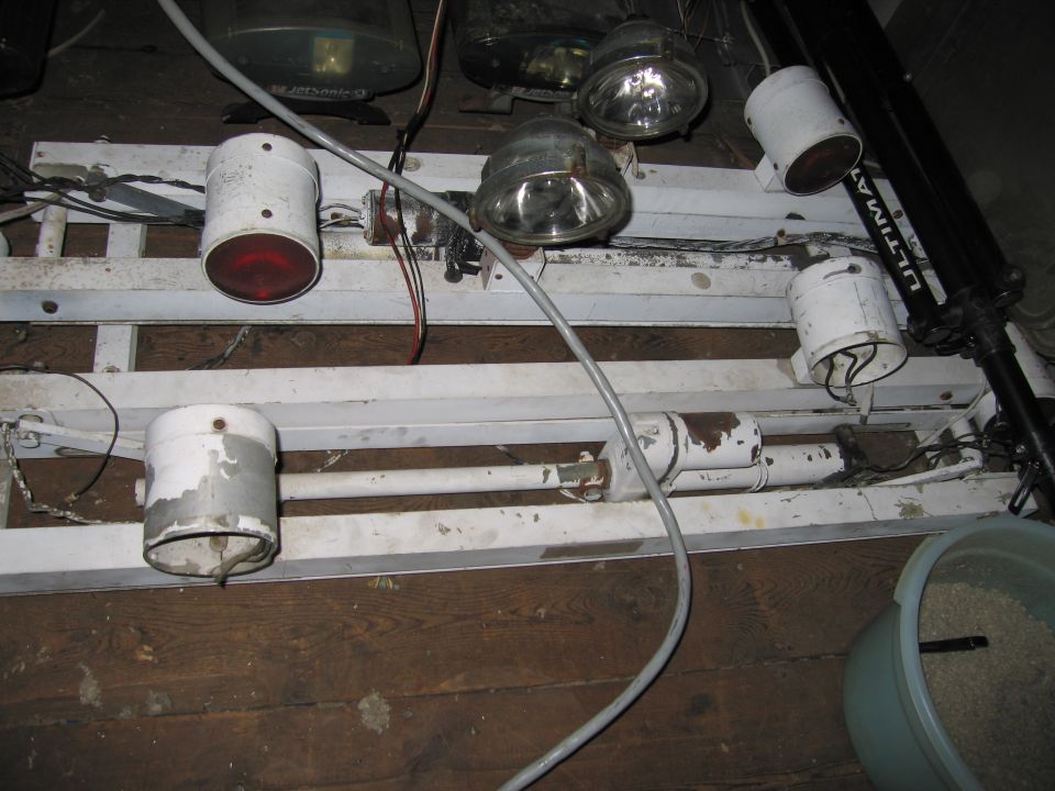 White metal lighting rig with multiple lights and wires on a wooden floor