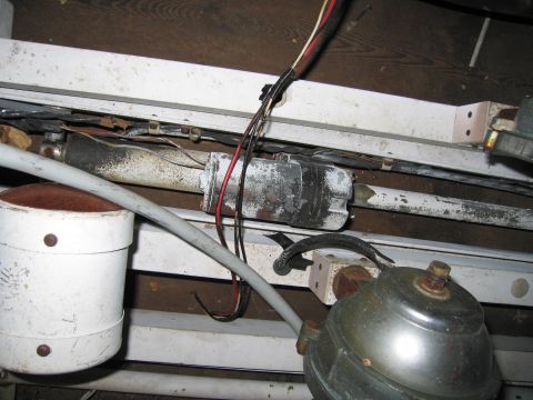 2001 Ford Crown Victoria - Dusty emergency-equipment parts on a wooden shelf: a white plastic rotating beacon housing with an orange-brown rotator, a chrome bell or s…