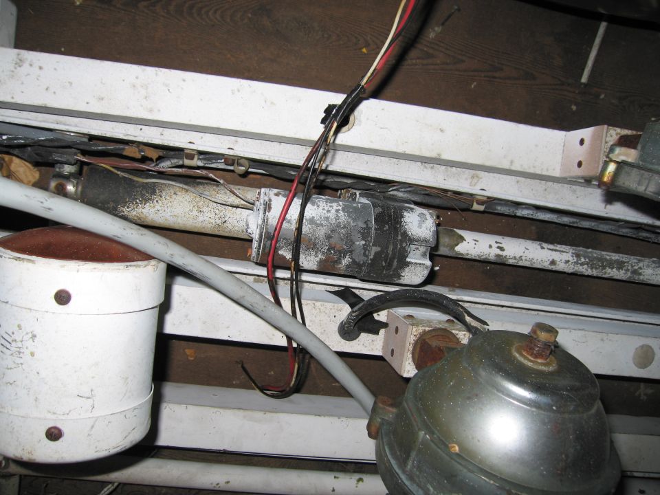 Disassembled beacon housing, chrome siren and light bar rails with loose wiring on shelf