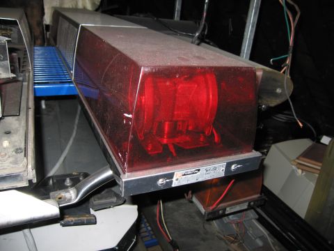 2001 Ford Crown Victoria - A Federal light bar with red lenses is mounted on a vehicle, showing visible wiring and dust.