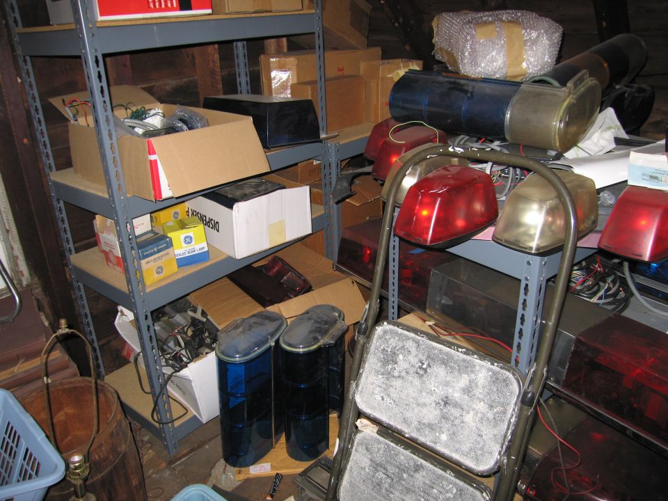 Storage shelves of vintage police lightbars, red beacon domes and sealed-beam lamp boxes
