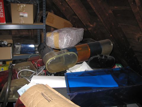 2001 Ford Crown Victoria - Various car parts are stored in a cluttered attic space under wooden rafters.
