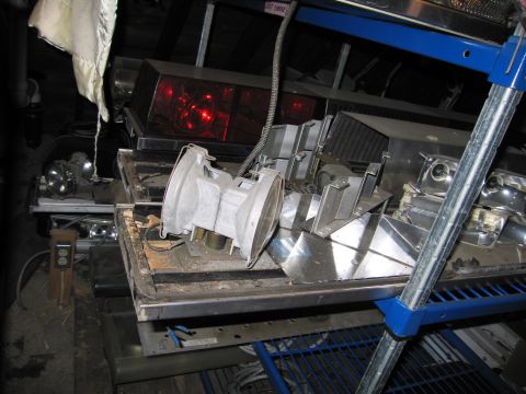 2001 Ford Crown Victoria - Various automotive light parts, including an emergency light bar, are stored on metal shelving units.