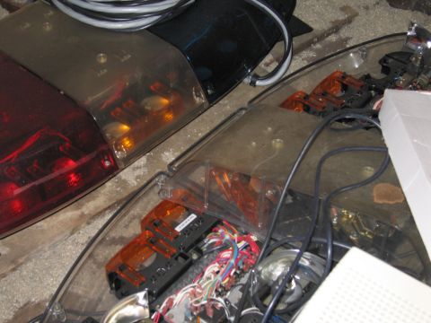 2001 Ford Crown Victoria - Disassembled emergency light bar components are laid out on a concrete surface.