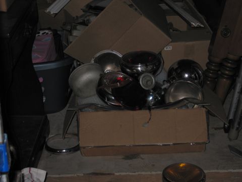 2001 Ford Crown Victoria - A collection of vintage vehicle headlights and chrome parts are stored in boxes.