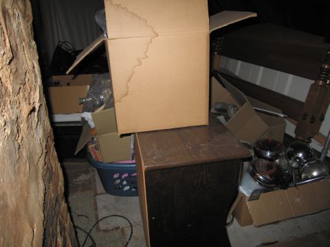 2001 Ford Crown Victoria - A disorganized storage space filled with various items, including boxes, a laundry basket, and what appear to be car parts.