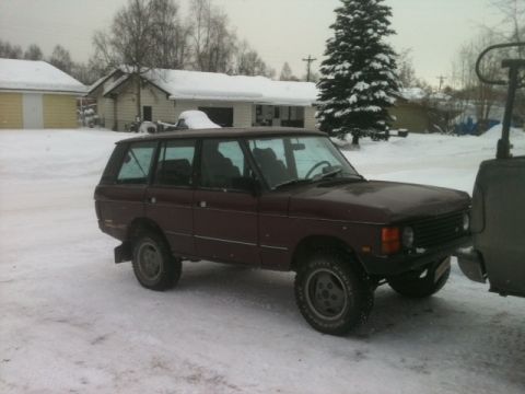 2001 Ford F-350 - A maroon Range Rover Classic is parked in a snowy environment, showing its 3/4 front profile.
