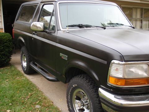 1993 Ford Bronco - This 1993 Ford Bronco is shown from a 3/4 front angle, highlighting its dark paint and classic SUV profile.