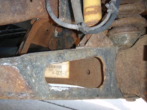 1993 Ford Bronco - A close-up view of a rusted vehicle frame component with a visible part number label.