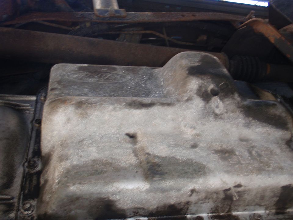 Ford logo on an oily oil pan, part of a vehicle's undercarriage