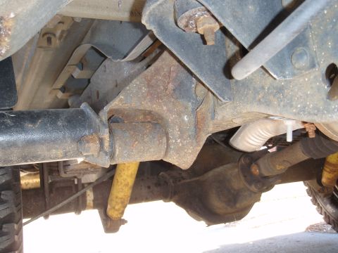 1993 Ford Bronco - The undercarriage of a vehicle, the rear axle and suspension system with visible signs of wear and rust.