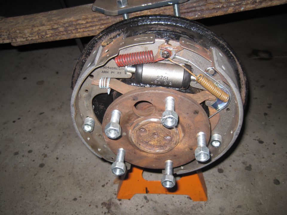 close-up of a vehicle's rear drum brake assembly with brake shoes, cylinder, and springs visible