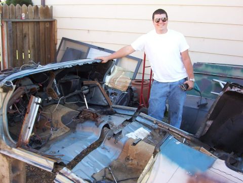 1978 Ford Mustang II - A man stands next to the gutted interior of a car, revealing its internal components and rusted structure.