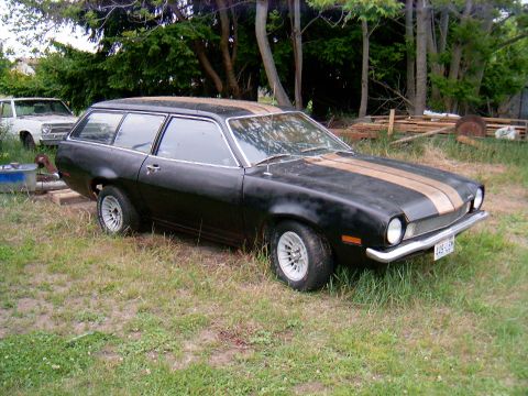 1978 Ford Mustang II - This black Ford Pinto wagon with gold racing stripes is parked in a grassy area next to another vehicle.