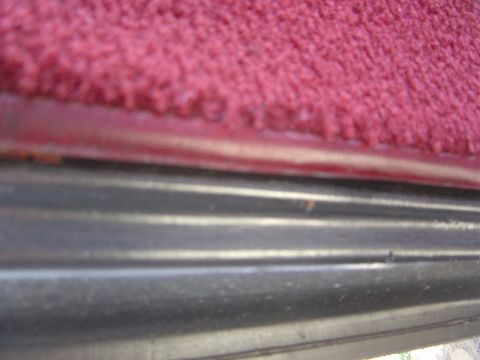 1986 Ford Bronco - Interior view showing red carpet and black trim panel.