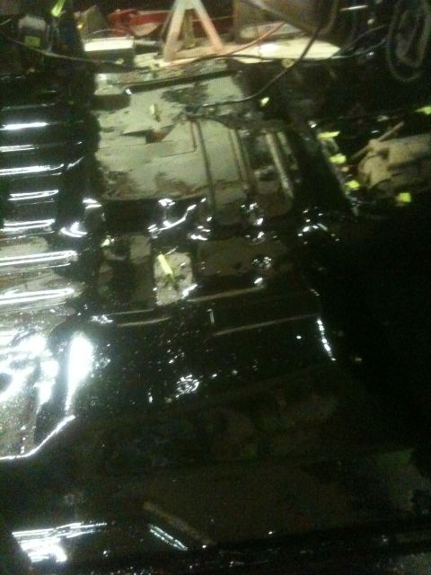 1993 Ford Bronco - The underside of a vehicle is coated in black, with some yellow markers visible.