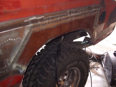 1979 Ford Bronco - Welding is being done on the rear fender of a vehicle, with a large tire visible.