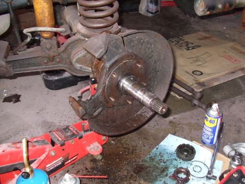 1979 Ford Bronco - Front wheel hub assembly, brake rotor, and suspension parts are visible in a garage setting.
