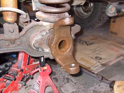 1979 Ford Bronco - Close-up of a rusty vehicle suspension component supported by red jack stands.