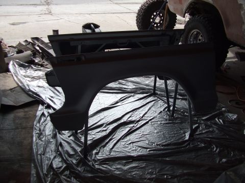 1979 Ford Bronco - A disassembled Ford Bronco fender is prepped for work, with another vehicle visible in the background.