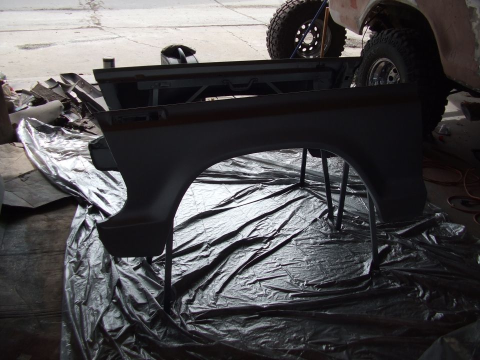 Dark gray Ford Bronco fender on stands over black plastic sheeting