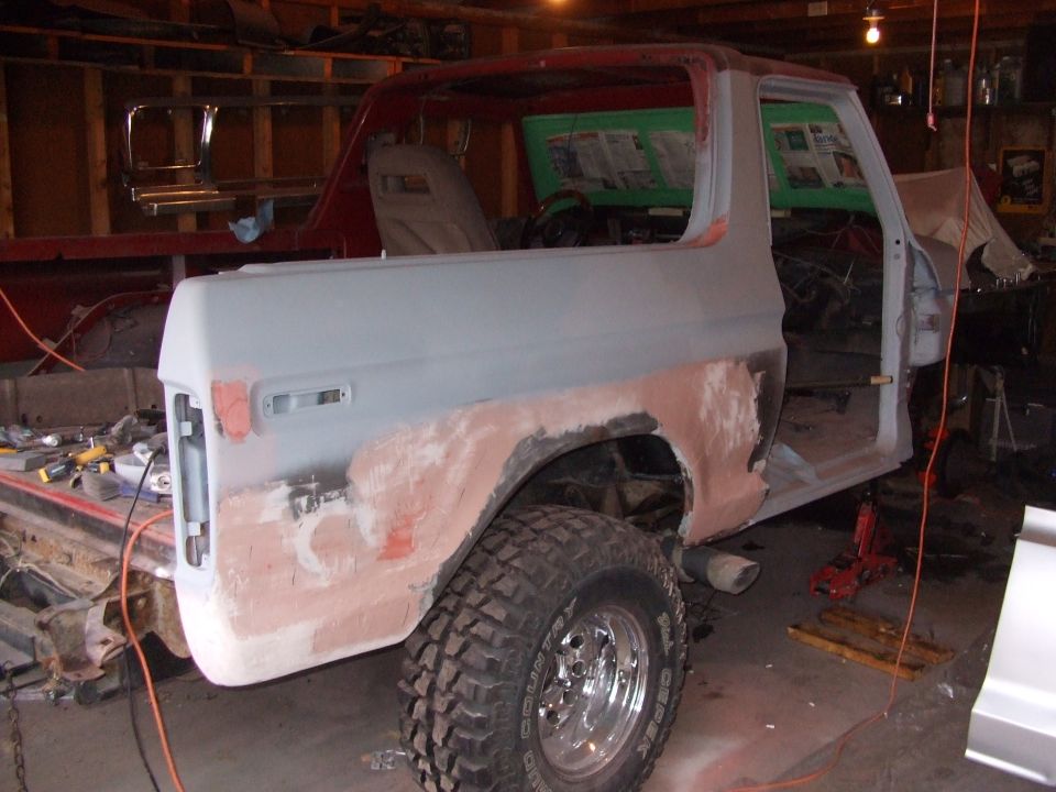 Ford Bronco bodywork in progress, primer applied to rear quarter panel, red roof, open doors