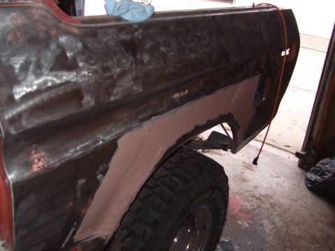 1979 Ford Bronco - The rear fender of a 1979 Ford Bronco shows extensive bodywork in progress, with primer and exposed metal visible.