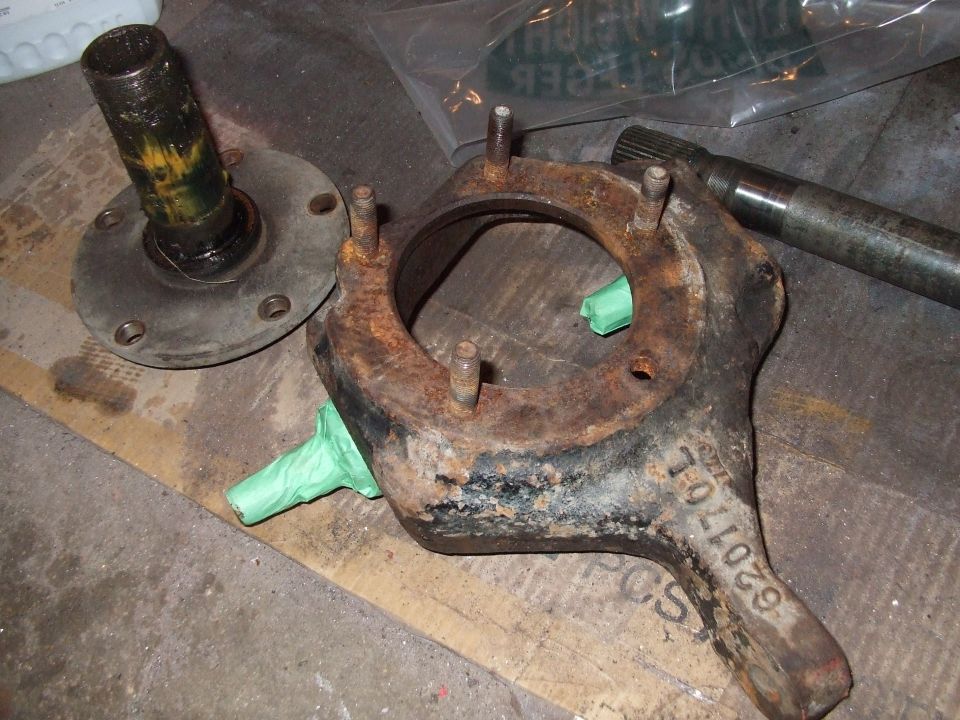 Vehicle spindle and hub assembly parts on a wooden surface. One part has a part number 620170L stamped on it