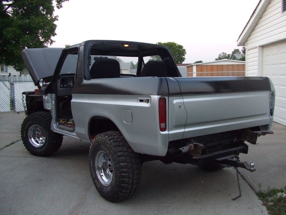 Ford Bronco with hood up and doors open, silver body with black top, parked in a driveway