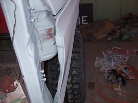 1979 Ford Bronco - The side view of a white 1979 Ford Bronco shows its door and tire, likely during a restoration project.
